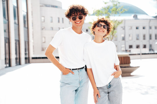 Young smiling beautiful woman and her handsome boyfriend in casual summer white t-shirt and jeans clothes. Happy cheerful family. Female having fun. Couple posing in street at sunny day. In sunglasses