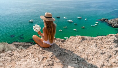 Woman travel sea. Happy woman in a beautiful location poses on a cliff high above the sea, with emerald waters and yachts in the background, while sharing her travel experiences