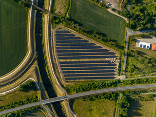 Top down drone shot of solar panels between fields, river and streets