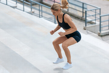 Blonde woman in sportswear jumping on the stairs