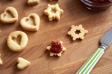 Fototapeta na wymiar Filling handmade Linzer Christmas cookies with strawberry marmalade