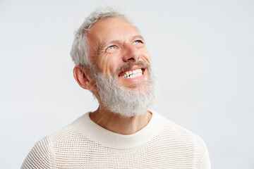 Portrait smiling handsome Scandinavian man with white teeth looking up isolated on white background. Health care, dental treatment concept. Happy gray haired bearded hipster after barbershop service