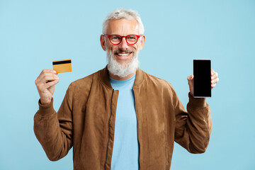 Smiling confident mature man, bearded hipster holding golden credit card, mobile phone shopping...