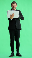 young man in full growth. isolated on green background using laptop