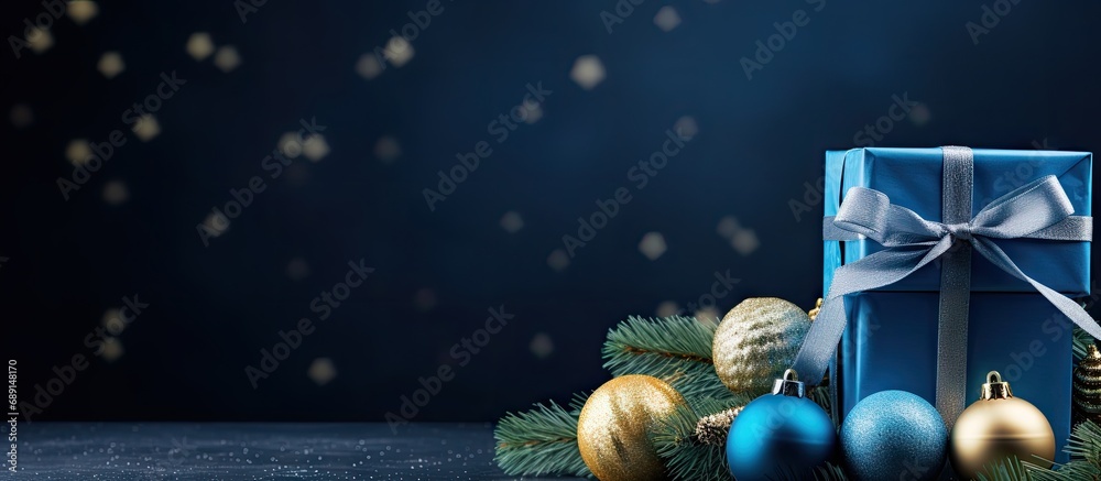 Aufkleber blue christmas themed gift with ribbon balls branches cones on dark blue background and room for tex