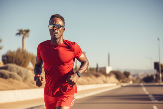 Focused african man triathlete running in sunny day