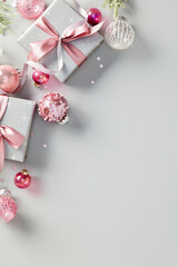 Christmas gift boxes with pink ribbon bows, pink baubles, fir branches on grey background. Xmas...