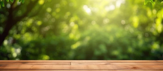 Papier Peint photo Jardin Nature themed background with a wooden table in a garden featuring bokeh in a spring summer setting The wood surface is versatile serving as a shelf counter desk and for picnic meals and produc