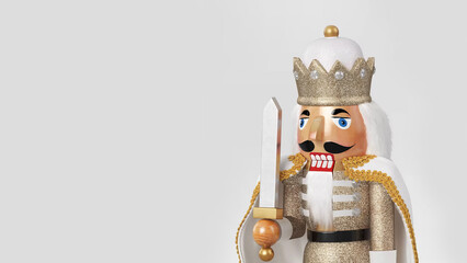 Closeup of traditional Christmas nutcracker with white clothes and cape, holding a sword, isolated...
