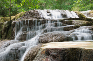 Obraz premium Wood table top podium in outdoors waterfall green lush tropical forest nature background.Organic healthy natural product present placement pedestal counter display,website banner cover jungle concept.
