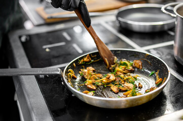 chef hold pan with mushroom and onion at the restaurant kitchen