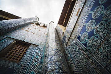 Facing the facade of a building with ancient glazed ceramic tiles in the ancient city of Khiva in...