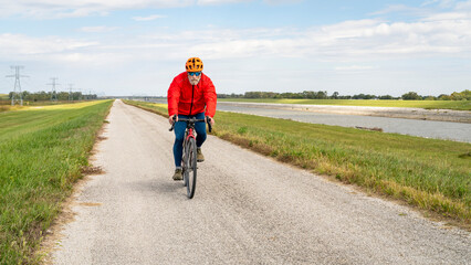 senior athletic man is riding a gravel touring bike - biking on a levee trail along Chain of Rocks Canal near Granite City in Illinois