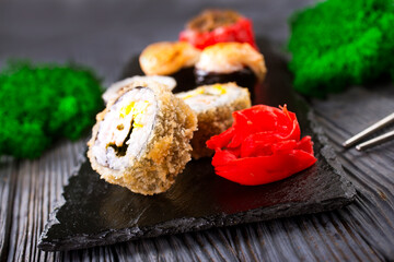Sushi roll with salmon, smoked eel, avocado, cream cheese on black background. Sushi menu. Japanese food.