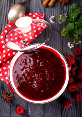 Raspberry jam with berry on dark background.