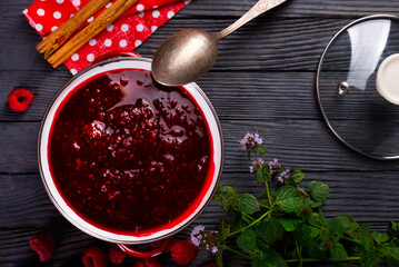 Raspberry jam with berry on dark background.