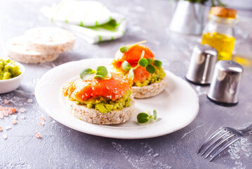 open sandwiches with rye bread, avocado, smoked salmon on a white plate
