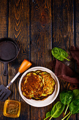 Homemade spinach pancakes on wooden background.