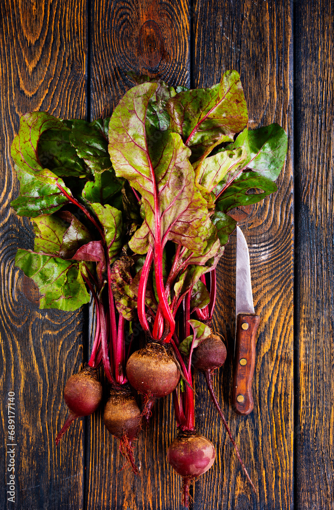 Wall mural fresh beets on cutting board, set on wooden table viewed from above