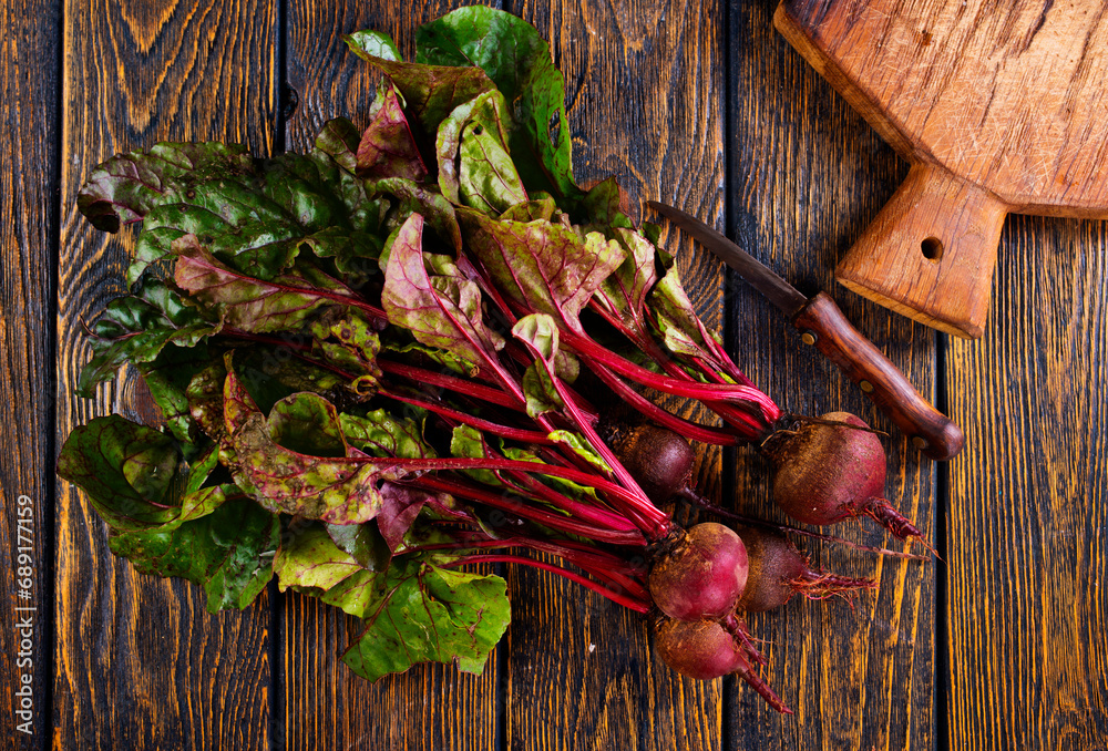 Poster fresh beets on cutting board, set on wooden table viewed from above