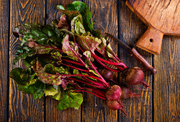 fresh beets on cutting board, set on wooden table viewed from above