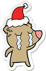 hand drawn sticker cartoon of a crying bear wearing santa hat
