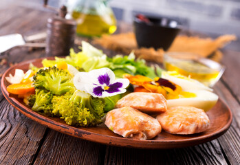 Fried salmon cutlets on a plate with vegetables and boiled eggs