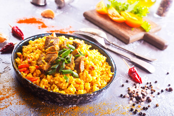 Pilaf, a dish of rice, chicken, carrots with spices and dried cranberries on a black plate
