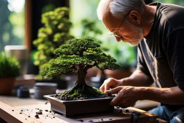 Keuken spatwand met foto An elderly man with glasses carefully tends to a lush bonsai tree on a wooden table © Cherstva