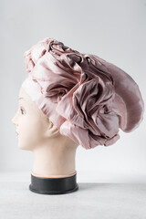 pink turban on a mannequin head, floral pink fashion turban on a white background