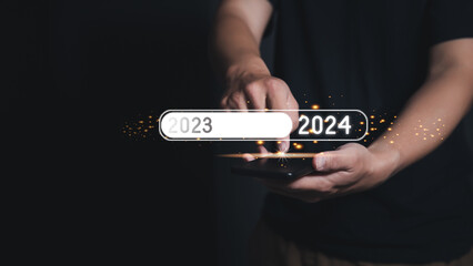 Man Finger pressing on smartphone to loading for changing the year 2023 to 2024. The new year 2024...