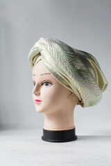 Gold turban on a mannequin head, pleated Gold fashion turban on a white background