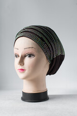 brown turban with rhinestones on a mannequin head, pleated brown fashion turban with diamante on a...
