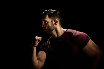 Portrait of brutal sporty strong guy with modern hairstyle isolated on black background, Low-key allure: A dramatic portrait of a dark, young man with a beard