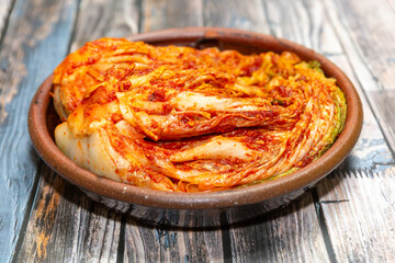 Kimchi, a traditional Korean fermented food made with cabbage in winter. A head of kimchi mixed with seasoning and served on a plate.