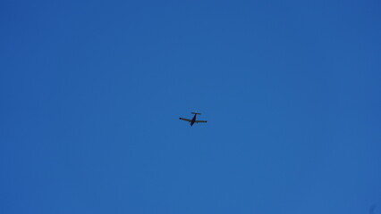An airplane flying through the clear blue sky in the sunny day
