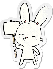 distressed sticker of a curious bunny cartoon with placard
