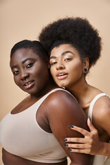 joyful plus size african american women in underwear looking at camera on beige, body positivity