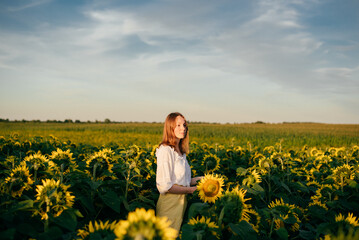 Fototapeta premium red-haired girl in a field with sunflowers