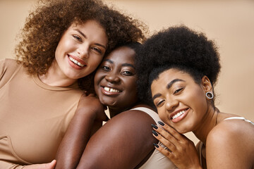 diverse multiracial body positive women in underwear smiling on beige backdrop, plus size beauty