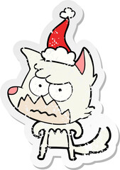 hand drawn distressed sticker cartoon of a annoyed fox wearing santa hat