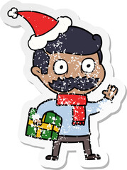 hand drawn distressed sticker cartoon of a man with mustache and christmas present wearing santa hat