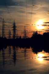 Silhouette high voltage electric tower on summer sunset background.