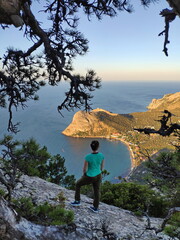 Photo of a girl stands on top of the mountain on the background of a sea bay at sunset in Crimea - 689215197