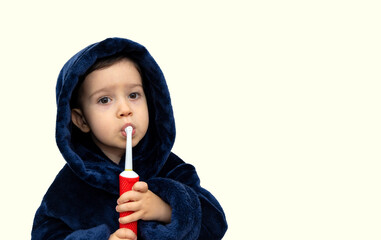 cute little baby boy in bathrobe isolated cleaning teeth with electric brush. mother hand help kid...