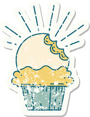 worn old sticker of a tattoo style cupcake with missing bite