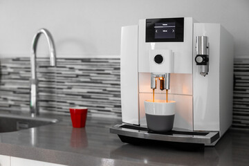 White automatic coffee maker on a gray countertop and some red accents