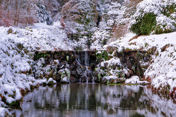 Winterlandschaft mit Bach und Wasserfall in einem Park in Kassel Wilhelmshöhe