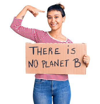 Young woman holding there is no planet b banner pointing finger to one self smiling happy and proud