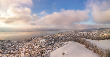 Winter magic on Lake Zurich, snow-covered idyll, clear air at golden hour over picturesque houses and trees, panoramic view from the air, Erlenbach in winter, panorama with the drone, travel location